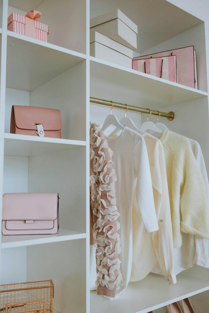 Stylish feminine wardrobe with clothes, bags, and gifts neatly organized on shelves.